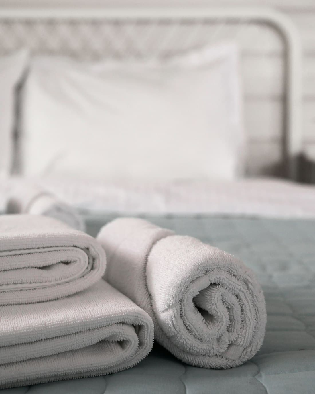 Soft rolled towels placed on a turned-down bed